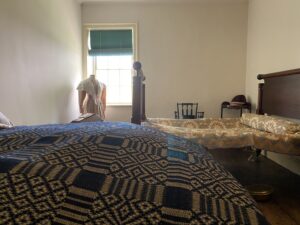 These two bedsteads are held together with ropes placed horizontally and vertically across the bed frame, to be tightened or loosened to the guest’s comfort. The mattress in the foreground is stuffed with period accurate materials of down and straw. 